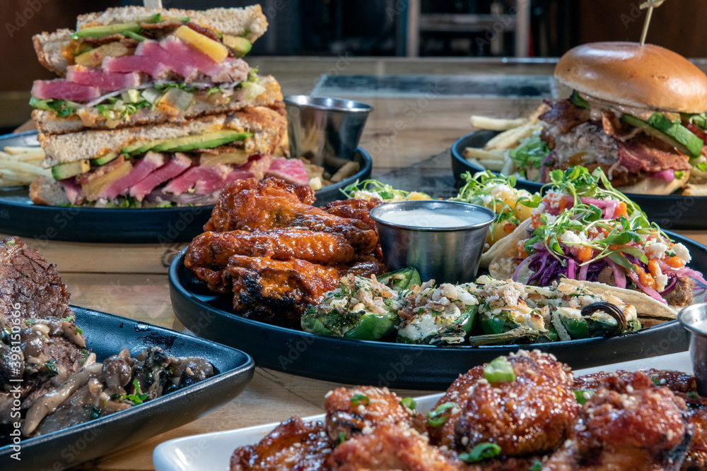 Full table of delicious meals straight from the grill including appetizer plate of tacos and stacked ahi tuna club sandwich. Full table of delicious meals straight from the grill including appetizer plate of tacos and stacked ahi tuna club sandwich.