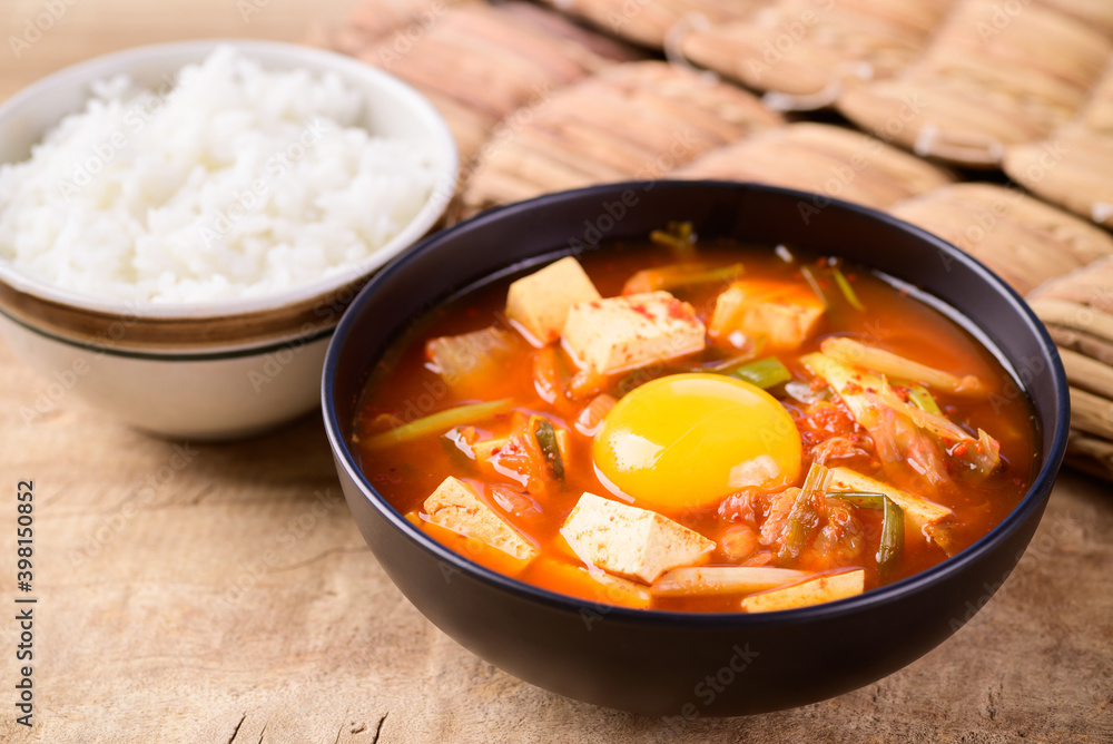 Korean food, Kimchi soup with fofu and egg eating with cooked rice on wooden background