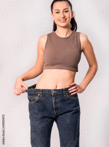 Dieting concept. Diet results. Before and after , fat and slim, losing weight. Caucasian girl. Slimming young woman wearing big pants on light grey background horizontal banner