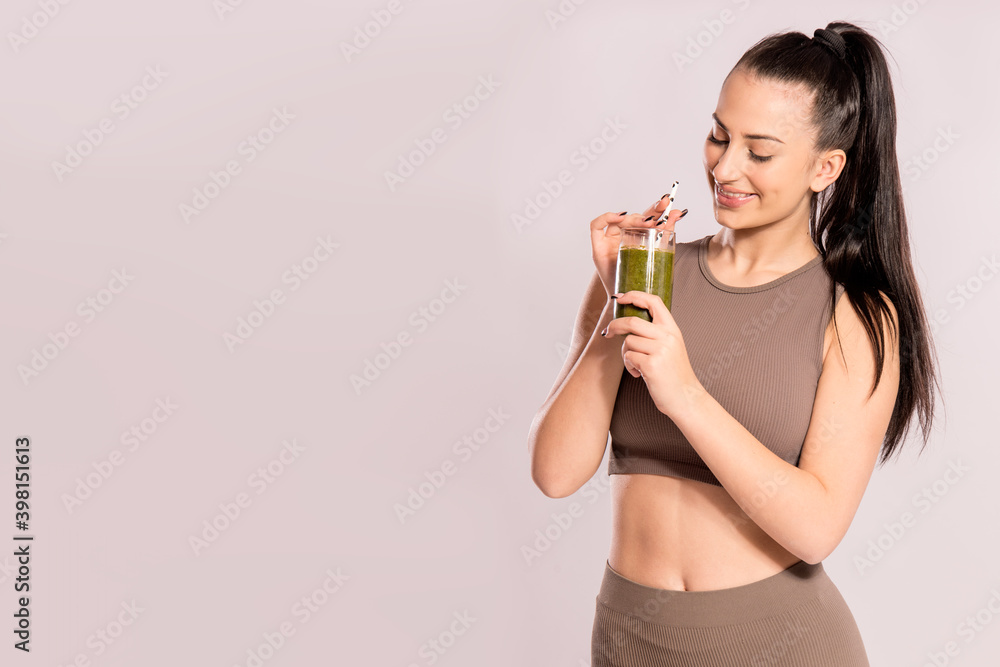 Young girl holding green smoothie standing on light grey background banner. Concept of fitness and detox Young girl holding green smoothie standing on light grey background banner. Concept of fitness and detox