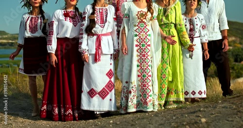 Group of singers in folk song costumes, beautiful rural landscape. Women in dresses with embroidery and wreaths of flowers on their heads, traditions and customs of the Slavic peoples. 4k, ProRes