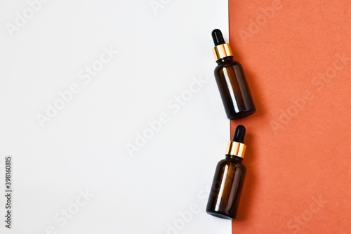 Two dropper oil bottles. Serum oil in glass bottles with a dropper on a pink-white background. Natural organic cosmetic, eco lotion, essence, serum. Copy space, flat lay. Advertising.