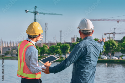 Two people worker Engineer talking discussion by tablet on site building real estate construction