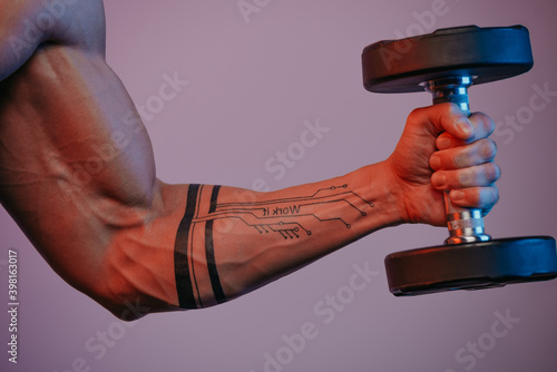 Fotografía A close photo of a muscular arm which is doing bicep curls with a dumbbell under blue and red lights
