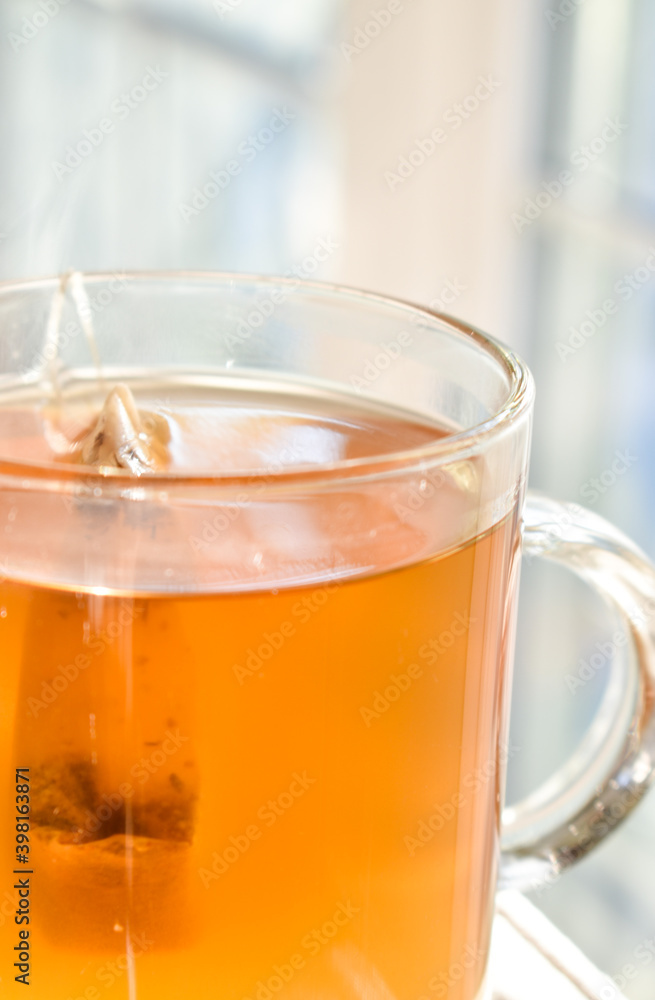 A beautiful glass filled with golden tea in the afternoon sunlight.