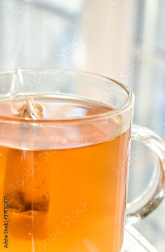 A beautiful glass filled with golden tea in the afternoon sunlight.