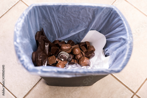Tempting unhealthy chocolates disposed of in a garbage can at the beginning of a diet