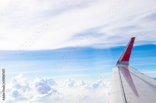 Plane wings in the sky with fluffy white clouds