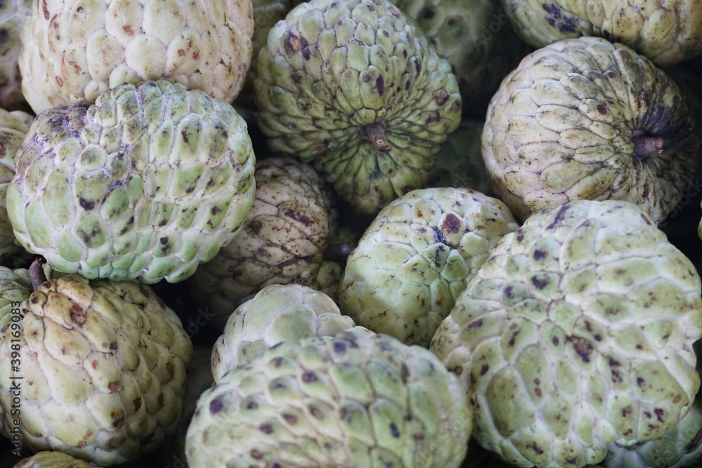 Close up of a bunch of green apples. Stack of sugar apple or Annona squamosa in a traditional market or fruit shop. Close up of a bunch of green apples. Stack of sugar apple or Annona squamosa in a traditional market or fruit shop.
