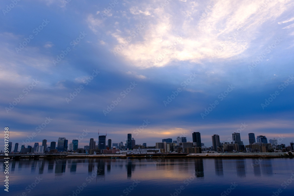 大阪淀川河川敷から見た梅田。早朝厚い雲からわずかに朝日が顔を出す