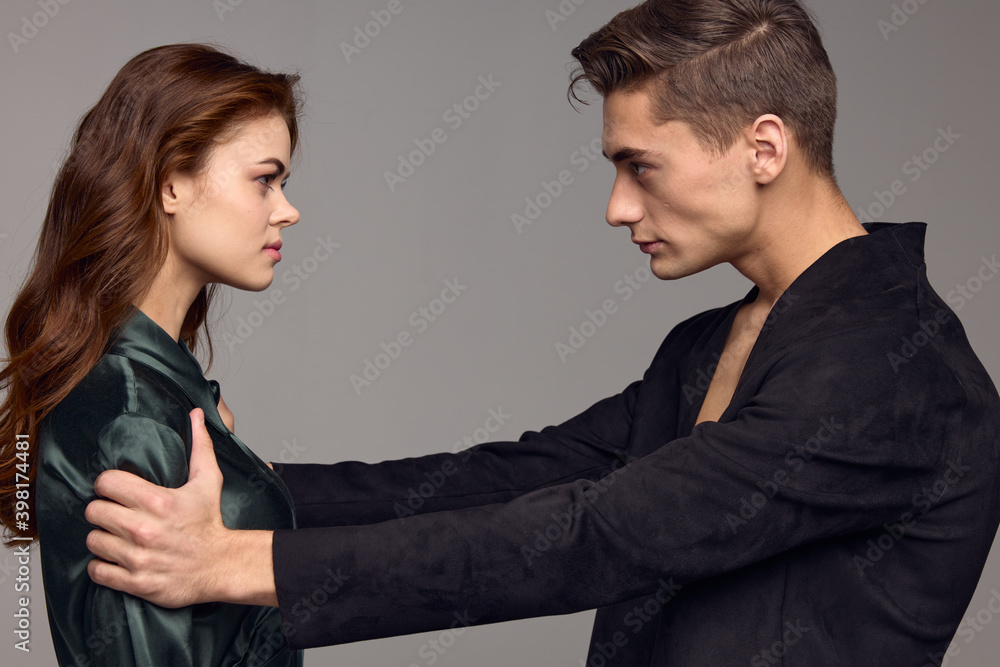 Sexy man in a jacket and a woman on a gray background opposite each other Sexy man in a jacket and a woman on a gray background opposite each other