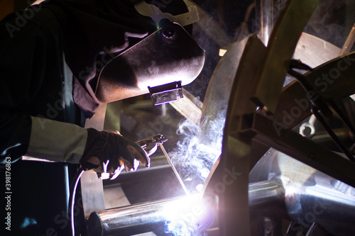 Metal workers use manual labor, Skilled welder, Factory workers making OT. Welder is welding the steel in the factory. © niwat