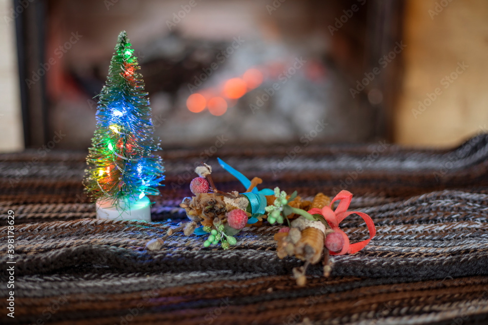 Christmas tree with lights and candles on the background of a stone fireplace with wood. cozy house waiting for christmas horizontal