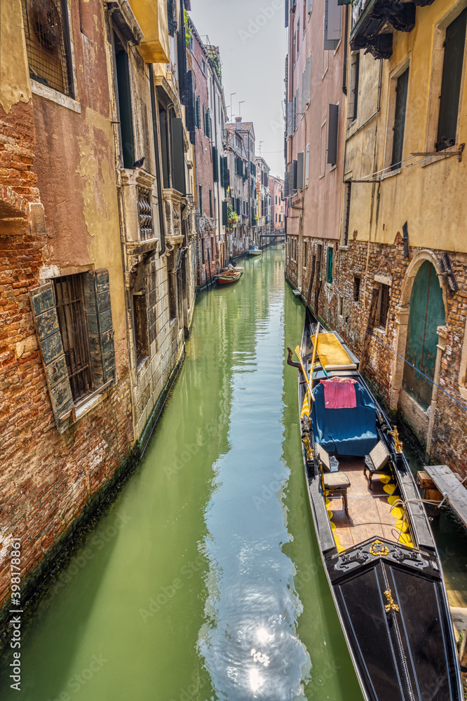 Small canal with traditional gondola seen in Venice, Italy