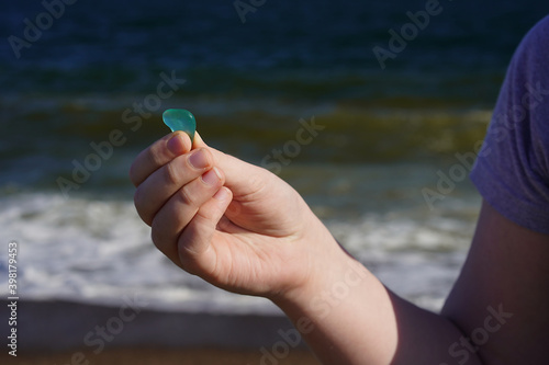 Child's hand with sea glass on the sea background.