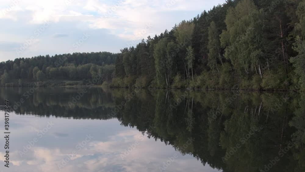 Quiet fishing lake without waves. Reflection of forest on the shore in smooth water. Quiet fishing lake without waves. Reflection of forest on the shore in smooth water.