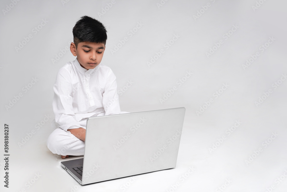 Cute indian boy using laptop over white background