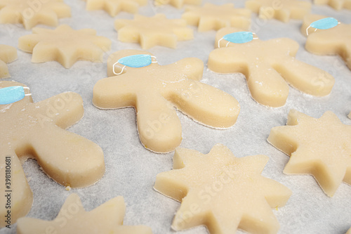 Short bread cookies in shape of stars and gingerbread man with face masks piped on. Concept for Christmas cookie baking during covid. Traditional Christmas sugar cookie from Switzerland Mailaenderli.