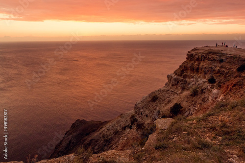 Seascape at red sunset. On the edge of a cliff. Summer-autumn. Horizontal photo. A soft picture. The view from the top