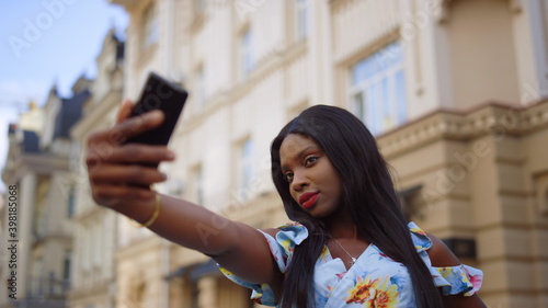 Photo Charming afro girl posing on phone camera on street