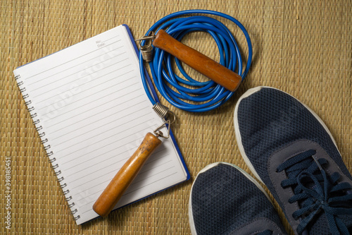 A notebook, sport shoes and skipping rope with a copy space. Flat lay view concept.