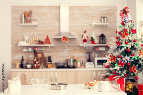 Ingredients for delicious cookies on christmas day on empty room. Kitchen on christmas day with nobody in the room decorated with x-mas tree and garlands photo