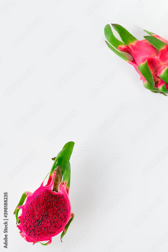 Fototapeta premium Creative flat layout with fresh organic pink dragon fruit, pitaya or pitahaya cut in half. Trendy top view on white background with text space.