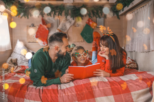 Happy family reading book in motorhome on Christmas eve