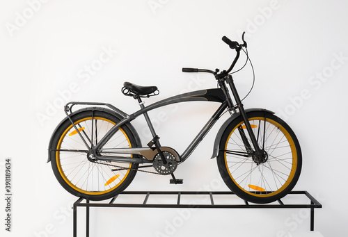 Modern bicycle near light wall