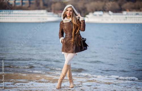 fashion outdoor photo of gorgeous sensual woman with blond hair in elegant clothes and luxurious coat, walking by winter city