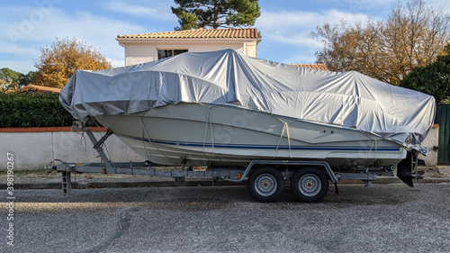 boat under tarpaulin tarp on car trailer