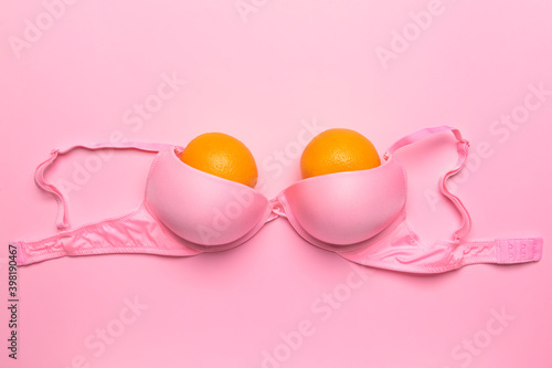 Ripe oranges in bra on color background