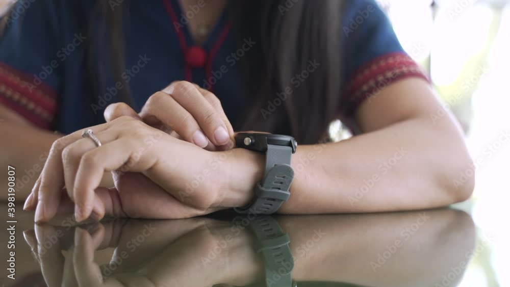 An Asian woman adjust or check her smart watch with fingertip for blood pressure monitoring An Asian woman adjust or check her smart watch with fingertip for blood pressure monitoring