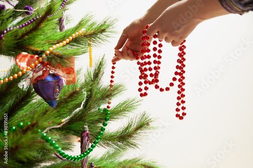 Hands hang garland on Christmas tree close up