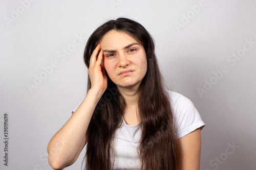 A tired woman holds her head with her hand, her head hurts. Brain vascular spasm, hypertension, high blood pressure after stress at work. Fatigue and excruciating headache