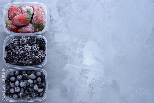 Frozen berries in boxes on gray background with copy space