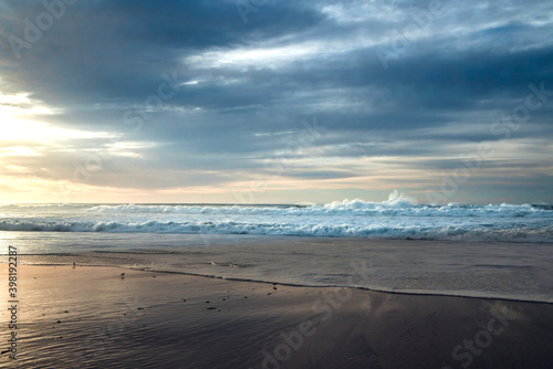 Sunset on the beach. Stormy ocean and beautiful cloudy sky on background