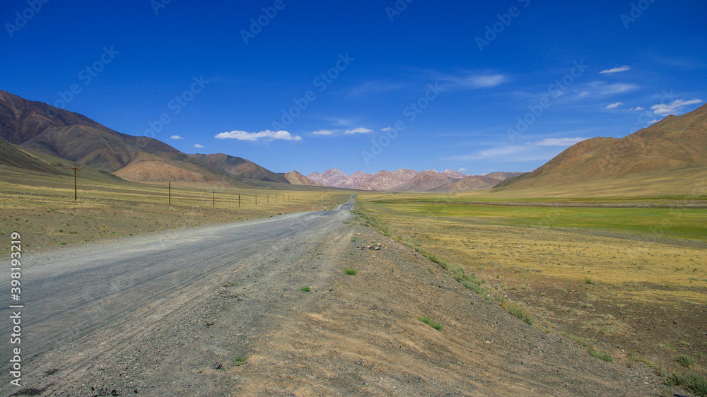 Scenic mountain landscape of long straight stretch of road on high-altitude Pamir Highway near Murghab, Gorno-Badakshan, Tajikistan