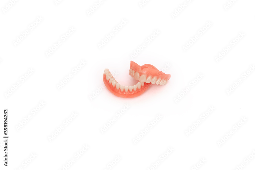 Full removable plastic denture of the jaws. Set of dentures on a white background. Two acrylic dentures. Upper and lower jaws with fake teeth. Dentures or false teeth, close-up. Copy space Full removable plastic denture of the jaws. Set of dentures on a white background. Two acrylic dentures. Upper and lower jaws with fake teeth. Dentures or false teeth, close-up. Copy space