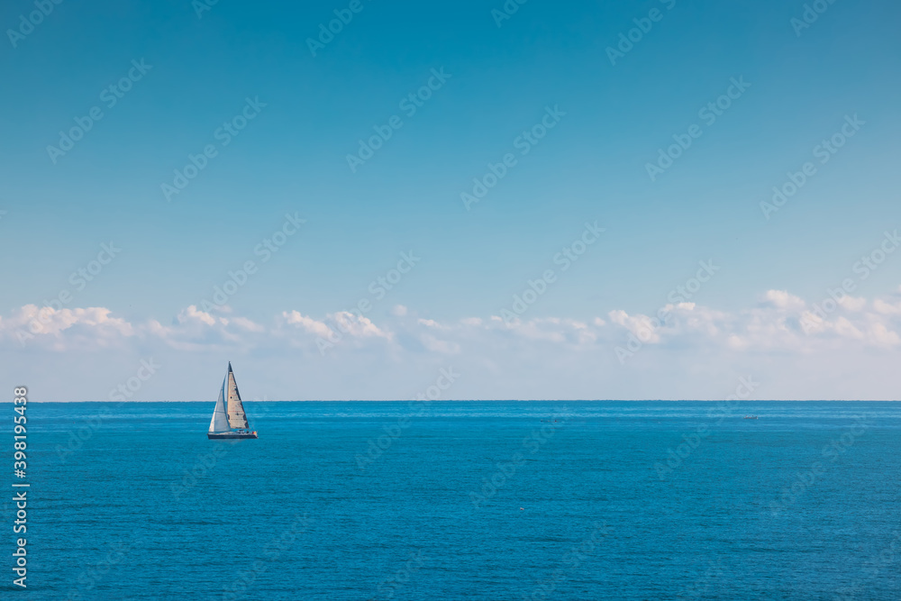 Sea and sailing wind boat. Sailboat over blue waves and sunny sky