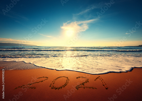 Beautiful sunrise over the sea. Happy New Year 2021 written on seashore.