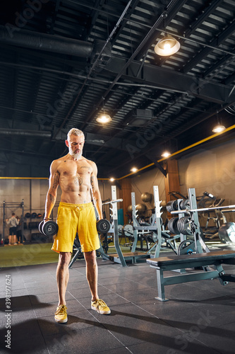 Athlete with hand weights standing at the gym