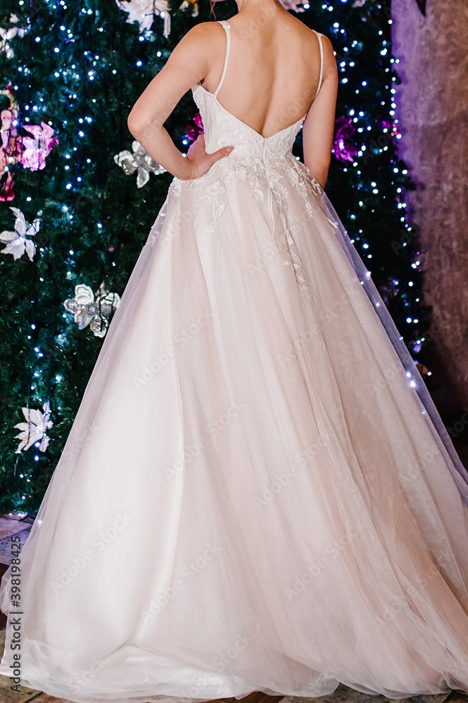Fototapeta premium Bride in expensive, luxury dress near christmas tree in wedding winter day. Woman, details of models on the collection.