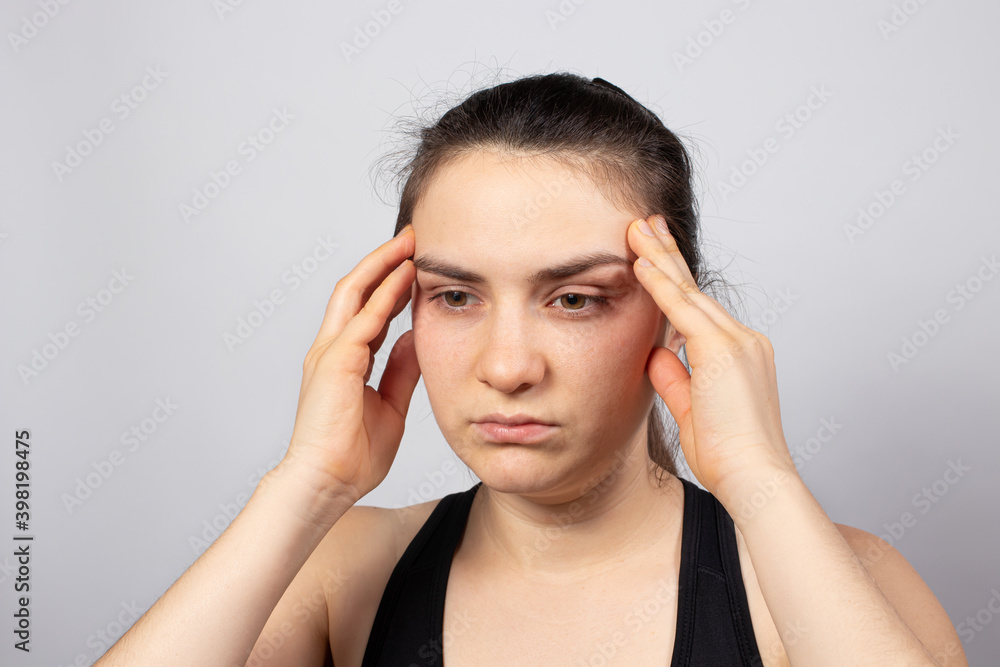The girl holds her hands by the temple on a light white background. Concentration, concentration and meditation, headache. Tired view The girl holds her hands by the temple on a light white background. Concentration, concentration and meditation, headache. Tired view