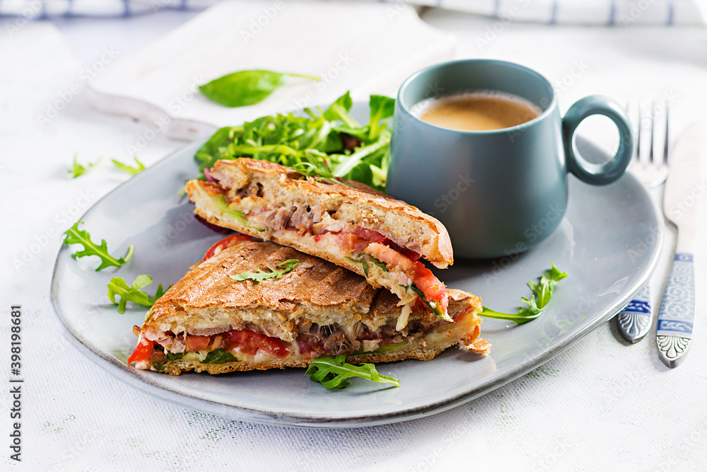 Grilled club sandwich panini with beef, tomato, cheese, lettuce and cup of coffee. Delicious breakfast or snack. Grilled club sandwich panini with beef, tomato, cheese, lettuce and cup of coffee. Delicious breakfast or snack.
