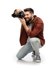 photography, profession and people and concept - happy smiling man or photographer with digital camera staying on one knee and taking picture over white background