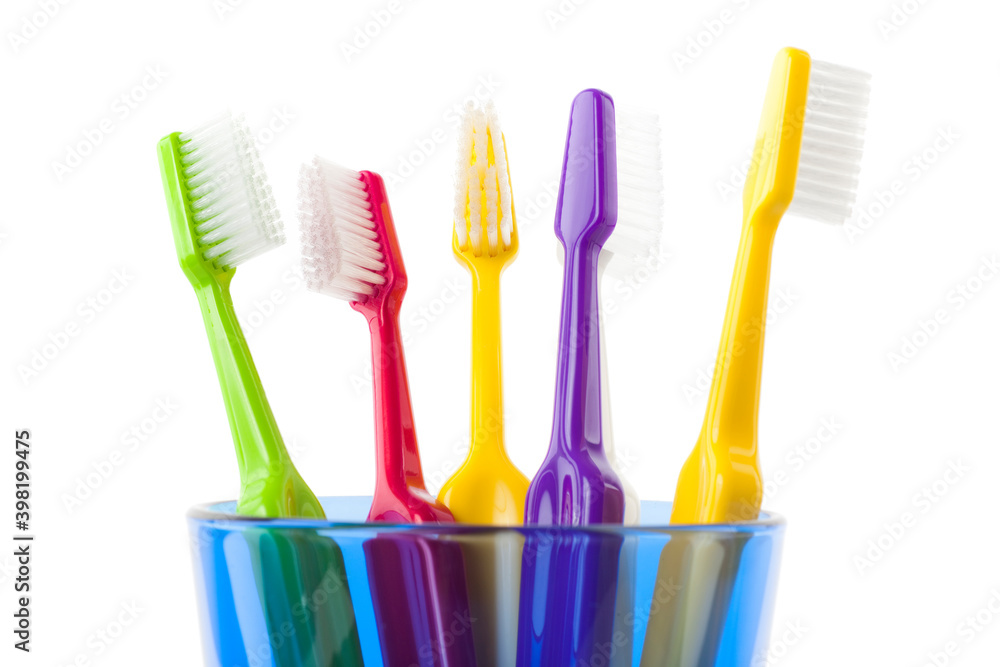 A group of colorful toothbrushes in a blue glass. Studio photo isolated on white background. Selective focus on object. A group of colorful toothbrushes in a blue glass. Studio photo isolated on white background. Selective focus on object.