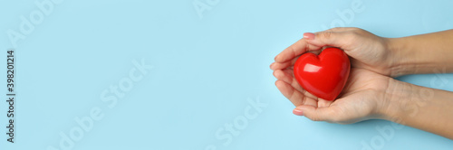 Female hands holding heart on blue background  space for text