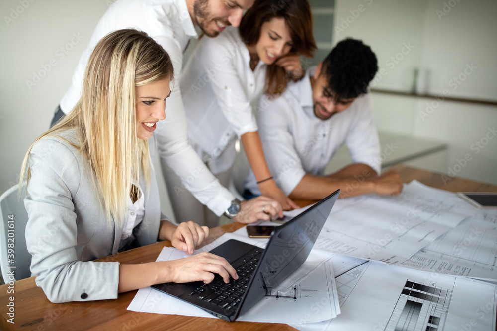 Team of architects working on construction plans in office Team of architects working on construction plans in office