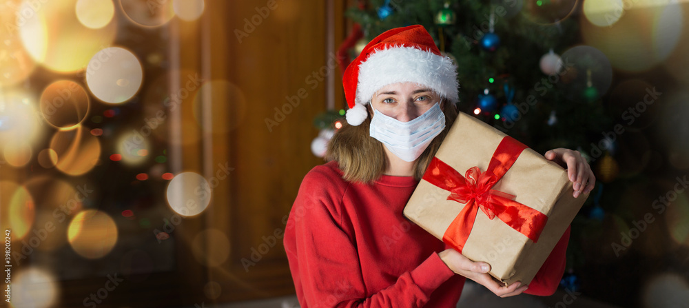 girl in red clothes and medical mask unfold New year gifts. the concept of celebrating Christmas midnight. Holiday's decor boce, Christmas tree
